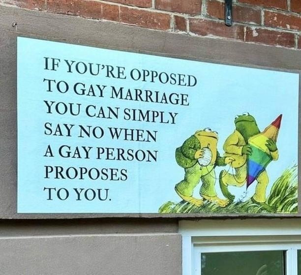 A sign on a brick wall reads: "IF YOU'RE OPPOSED TO GAY MARRIAGE YOU CAN SIMPLY SAY NO WHEN A GAY PERSON PROPOSES TO YOU." At right, a storybook illustration shows Frog and Toad walking through grass, Toad holding a ball of string and Frog holding a rainbow kite.