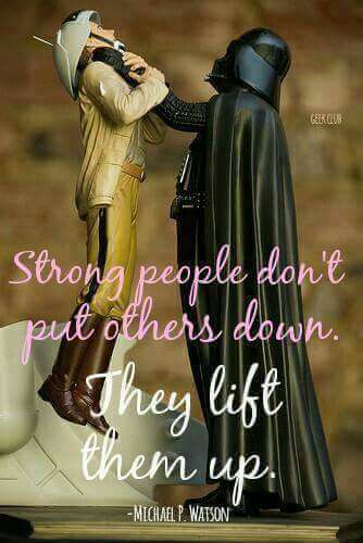 A collectible figurine of Darth Vader in black armor and cape holding a figure in a tan flight suit and white helmet off the ground by the throat. Pink and white script text reads: "Strong people don't put others down. They lift them up." Below it: "-Michael P. Watson". Small watermark: "GEEK CLUB".
