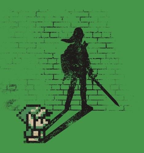 Green T-shirt-style illustration of a small, pixelated 8-bit Link sprite crouching at the lower left. On a black brick wall behind him, his shadow stretches up as a realistic, detailed silhouette of a tall Link holding a sword and shield. The image contains no text.
