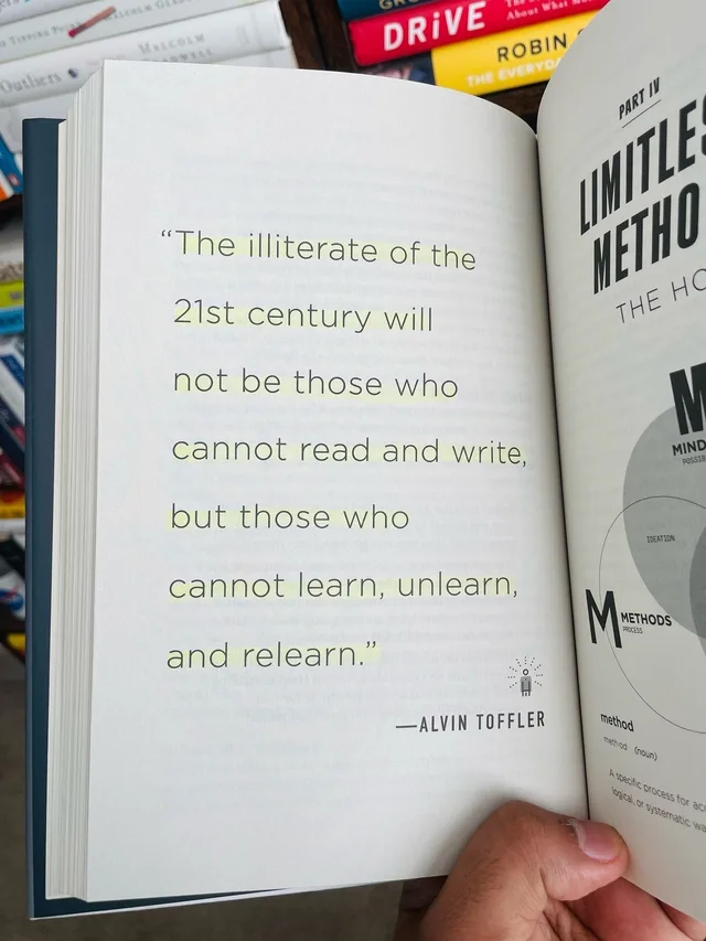 A hand holds open a hardcover book with yellow-highlighted text on the left page: "The illiterate of the 21st century will not be those who cannot read and write, but those who cannot learn, unlearn, and relearn." —ALVIN TOFFLER. The right page shows "Part IV, Limitless Methods" and a Venn diagram labeled Methods.