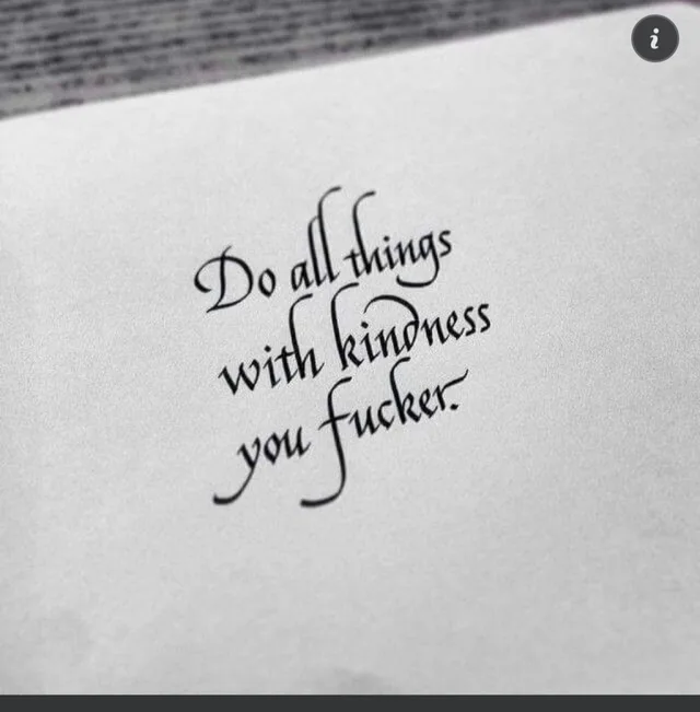 Black calligraphy on a gray paper surface, written in a slanted italic hand: "Do all things with kindness you fucker." A small dark circle with a white letter i sits in the top right corner.