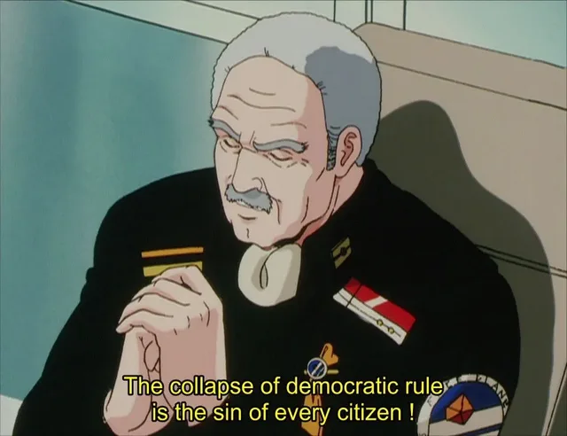 Anime screenshot of an elderly man with gray hair and a mustache in a black military uniform with insignia, hands clasped, eyes lowered. Yellow subtitle reads: "The collapse of democratic rule is the sin of every citizen !"