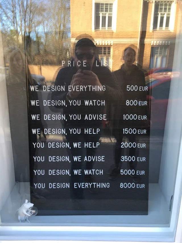 Photo of a black letterboard in a shop window, with reflections of two people and a building. It reads: PRICE LIST. WE DESIGN EVERYTHING 500 EUR. WE DESIGN, YOU WATCH 800 EUR. WE DESIGN, YOU ADVISE 1000 EUR. WE DESIGN, YOU HELP 1500 EUR. YOU DESIGN, WE HELP 2000 EUR. YOU DESIGN, WE ADVISE 3500 EUR. YOU DESIGN, WE WATCH 5000 EUR. YOU DESIGN EVERYTHING 8000 EUR.