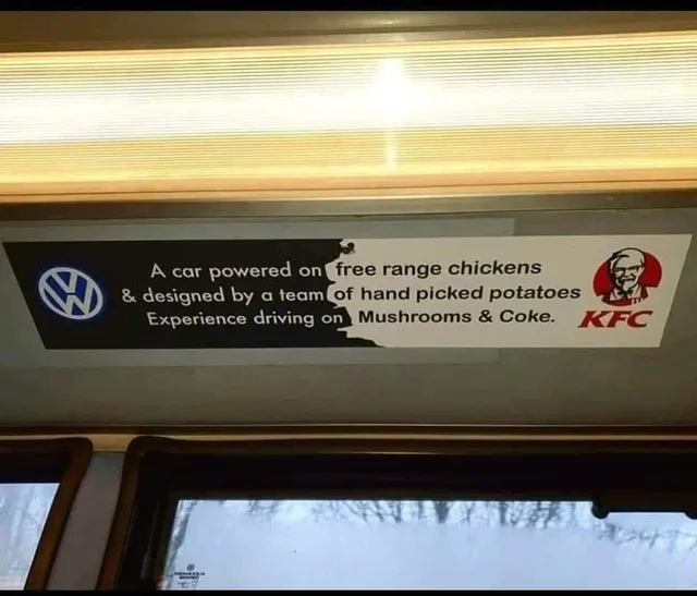 Photo of a bus ad strip under a light. Left side, black with a Volkswagen logo: "A car powered on & designed by a team Experience driving on". Right side, white with the KFC logo: "free range chickens of hand picked potatoes Mushrooms & Coke."