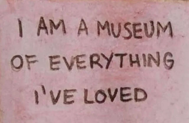 Hand-lettered dark brown capital letters on a mottled pink surface read: "I AM A MUSEUM OF EVERYTHING I'VE LOVED".