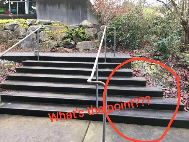 Photo of a wide concrete staircase with a metal handrail, outdoors beside rocks and shrubs. The right side of the steps tapers off into a dirt slope. A red hand-drawn circle surrounds the top-right steps, with red text reading: "What's the point???"
