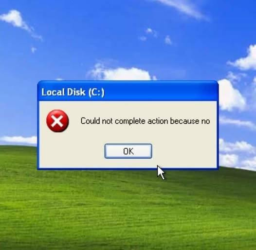 Screenshot of a Windows XP error dialog over the green hill and blue sky Bliss wallpaper. The title bar reads "Local Disk (C:)". A red X icon sits beside the text "Could not complete action because no" and an OK button. A mouse cursor points below it.