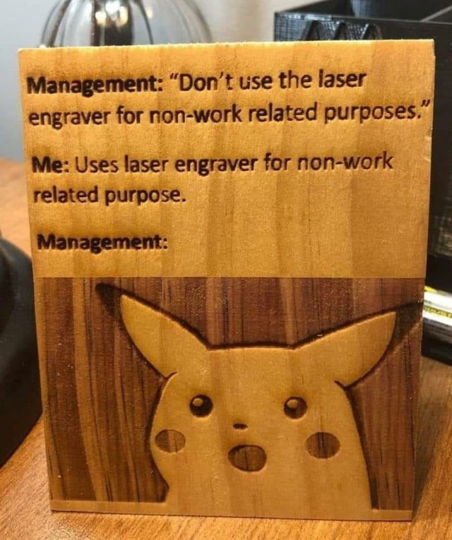 A wooden plaque laser-engraved with text and a carved Surprised Pikachu face. Text: "Management: "Don't use the laser engraver for non-work related purposes." Me: Uses laser engraver for non-work related purpose. Management:" Below is a carved Pikachu with an open mouth.