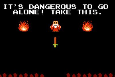 Pixel art screenshot from The Legend of Zelda on NES: on a black cave background, an old man in a red robe stands between two flickering fires above a sword. White text at the top reads: "IT'S DANGEROUS TO GO ALONE! TAKE THIS."
